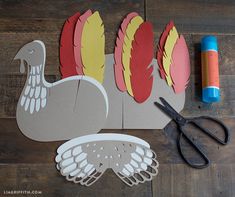 paper turkey cut out with scissors and glue on wooden floor next to crafting supplies