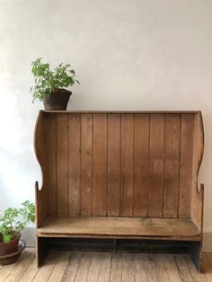 an old wooden bench with a potted plant on the top and bottom shelf next to it