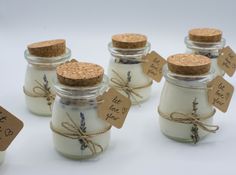 small jars filled with white candles and tied with twine, labeled with the names of each candle