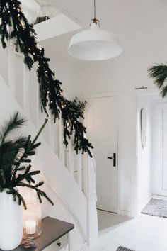 a white staircase decorated with christmas greenery and lights