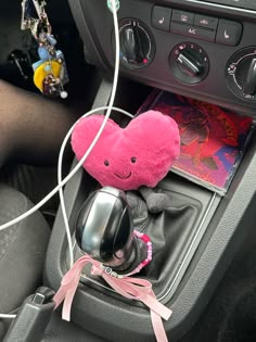 a pink stuffed animal sitting in the center console of a car with headphones attached to it