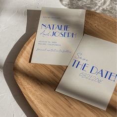 two blue and white save the date cards on a wooden tray