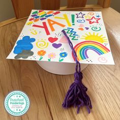 a decorated graduation cap on top of a wooden table with a purple tassel hanging from it