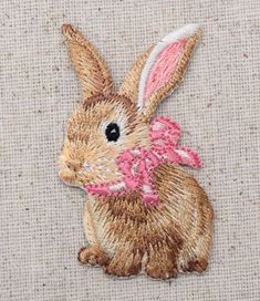 an embroidered rabbit with a pink bow on it's head