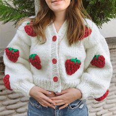 a woman wearing a white sweater with red strawberries on it and holding her stomach