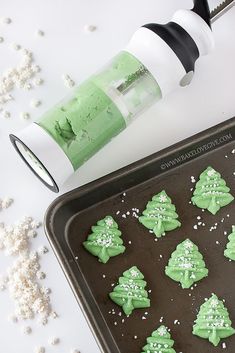 green frosted christmas tree cookies on a cookie sheet next to a baking utensil