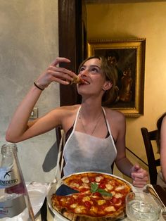 a woman sitting at a table with a pizza in front of her