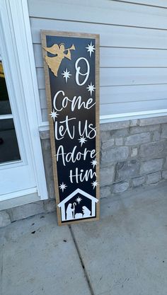 a black and white sign that says come let us adore him on the side of a house