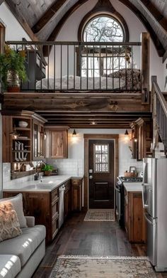 a kitchen and living room in a small house with wood accents on the ceiling, windows, and stairs