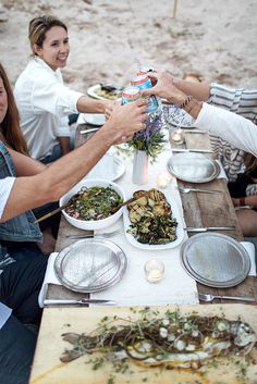 people sitting at a table with plates and bowls of food in front of each other