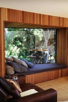 a living room with wood paneling and a window that looks out onto the woods