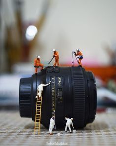 small figurines are placed on top of a camera lens to capture the scene