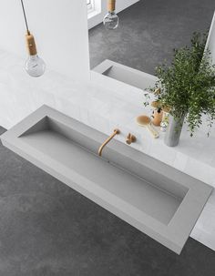 a bathroom with two sinks and plants in the middle, one sink has a wooden handle on it