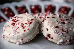 two cookies with white frosting and red sprinkles are on a plate