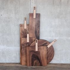 three wooden cutting boards sitting next to each other on top of a wood floor near a concrete wall