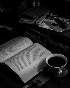 an open book sitting on top of a table next to a cup of coffee