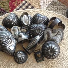 several metal objects are laying on a quilted tablecloth, some with hearts and other shapes