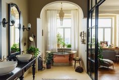 a bathroom with two sinks, mirrors and plants on the wall in front of it