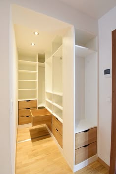 an empty walk in closet with white walls and wood flooring on the other side