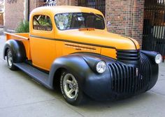 an orange and black truck parked on the side of a street next to a brick building