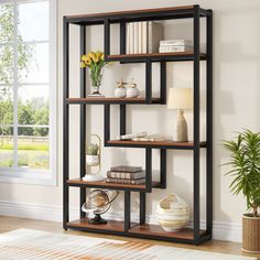 a book shelf with books and plants on it next to a potted plant in front of a window