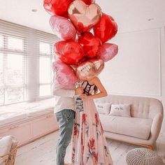 a man and woman holding red heart shaped balloons