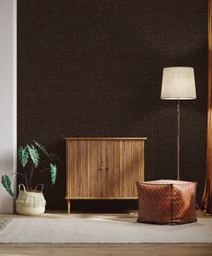 a living room with a lamp, sideboard and other items on the floor in front of a brown wall