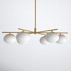 three white balls hanging from a brass chandelier with four lights on each end