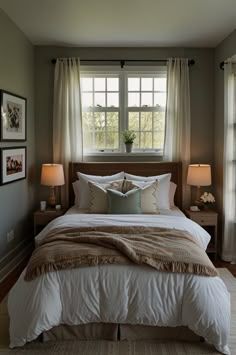 a bedroom with a bed, two lamps and pictures on the window sill above it