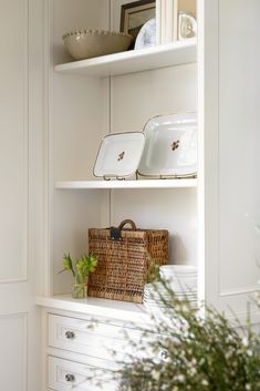 a white shelf filled with dishes and baskets