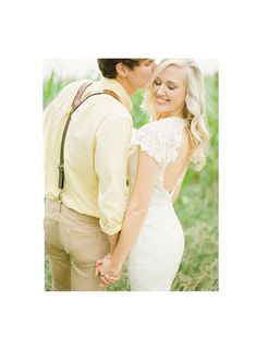 a man and woman are kissing in the middle of some tall grass with their backs to each other