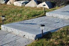 two lights that are sitting in the grass next to some rocks and grass on the ground