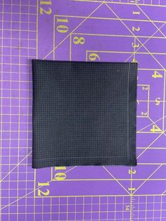 a piece of black fabric sitting on top of a purple cutting mat