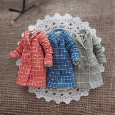 three miniature clothes are sitting on a doily