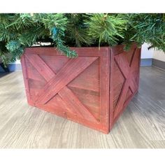 a wooden planter sitting on top of a hard wood floor next to a tree