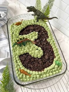 a dinosaur cake with green frosting and chocolate chips