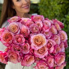 a woman holding a bouquet of pink roses