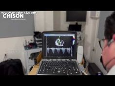 a man sitting in front of a laptop computer with sound waves on it's screen