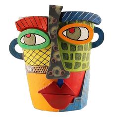 a colorful vase with an eye on the side and another face painted on it's sides