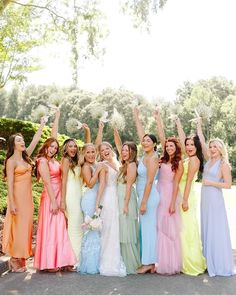 a group of women standing next to each other wearing dresses and holding their arms in the air