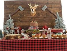 a table topped with cakes and cupcakes covered in frosting next to a wooden wall