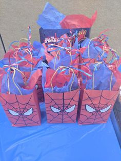 spider - man treat bags are sitting on a blue table with streamers in them