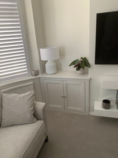 a living room with white furniture and a flat screen tv mounted on the wall above it