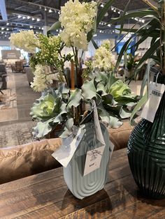 two vases filled with flowers sitting on top of a wooden table next to each other