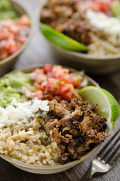 two bowls filled with rice, meat and veggies on top of a wooden table