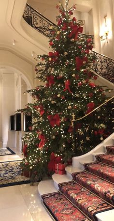 a christmas tree in the middle of a room with red and gold ornaments on it