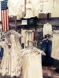 an american flag is hanging on the wall next to some dresses and other clothing in a store