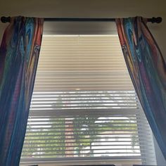 the window is covered with colorful curtains and drapes