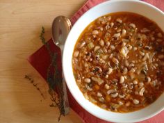 a white bowl filled with beans on top of a red napkin next to a spoon