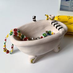 a white ceramic bathtub with beads on the rim and handles, sitting next to a banana